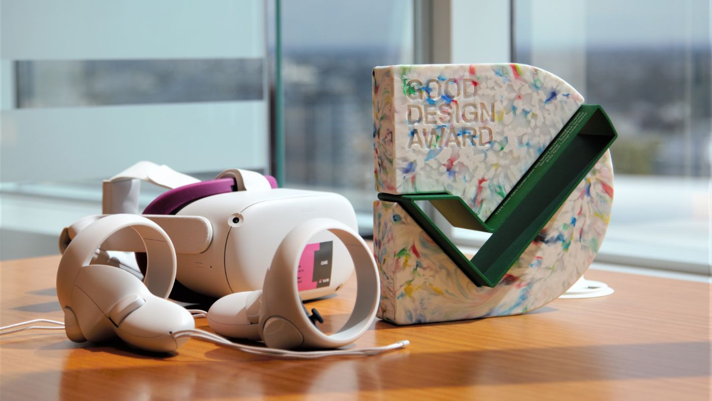 Virtual reality goggles sitting on a table next to a Good Design Award trophy
