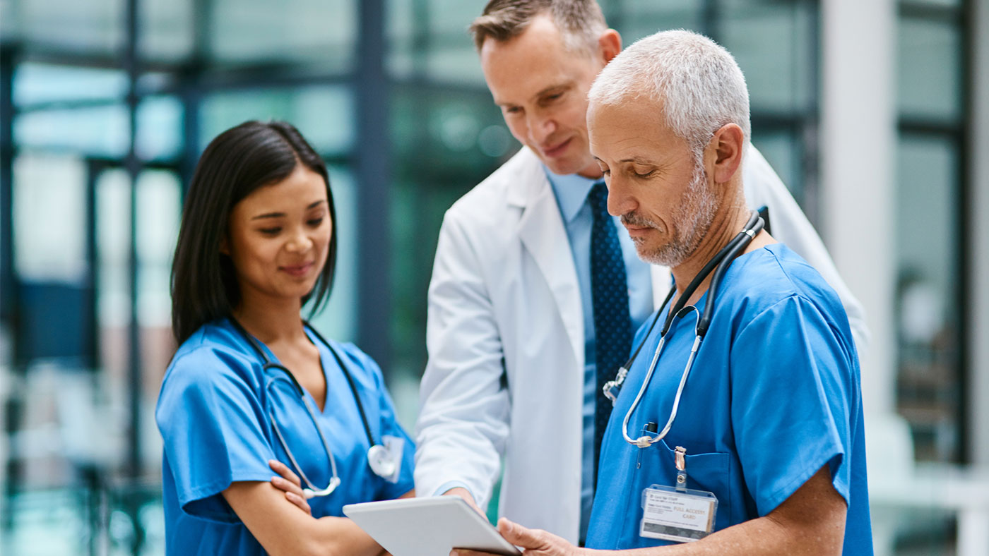 Group of medical practitioners working together on a digital tablet in a hospital.