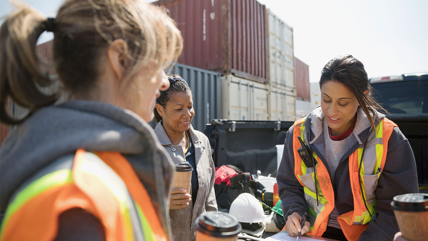 Three women on a construction site in hi visibility vests looking at some paperwork.